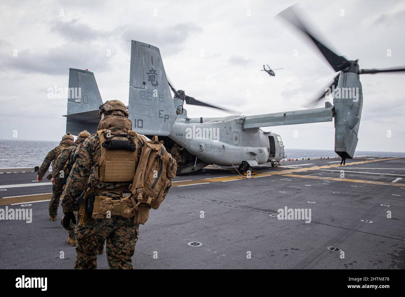 U.S Marines with Battalion Landing Team 1/5, 31st Marine Expeditionary Unit (MEU), board an MV-22B Osprey before conducting a helo-cast training exercise, aboard amphibious assault ship USS America (LHA 6), Feb. 17, 2022. The training exercise consisted of Marines jumping out of a low altitude CH-53E Super Stallion helicopter into the water, then climbing aboard an inflatable, motorized aircraft. The 31st MEU is operating aboard ships of Amphibious Ready Group in the 7th fleet area of operations to enhance interoperability with allies and partners and serve as a ready response force to defend Stock Photo