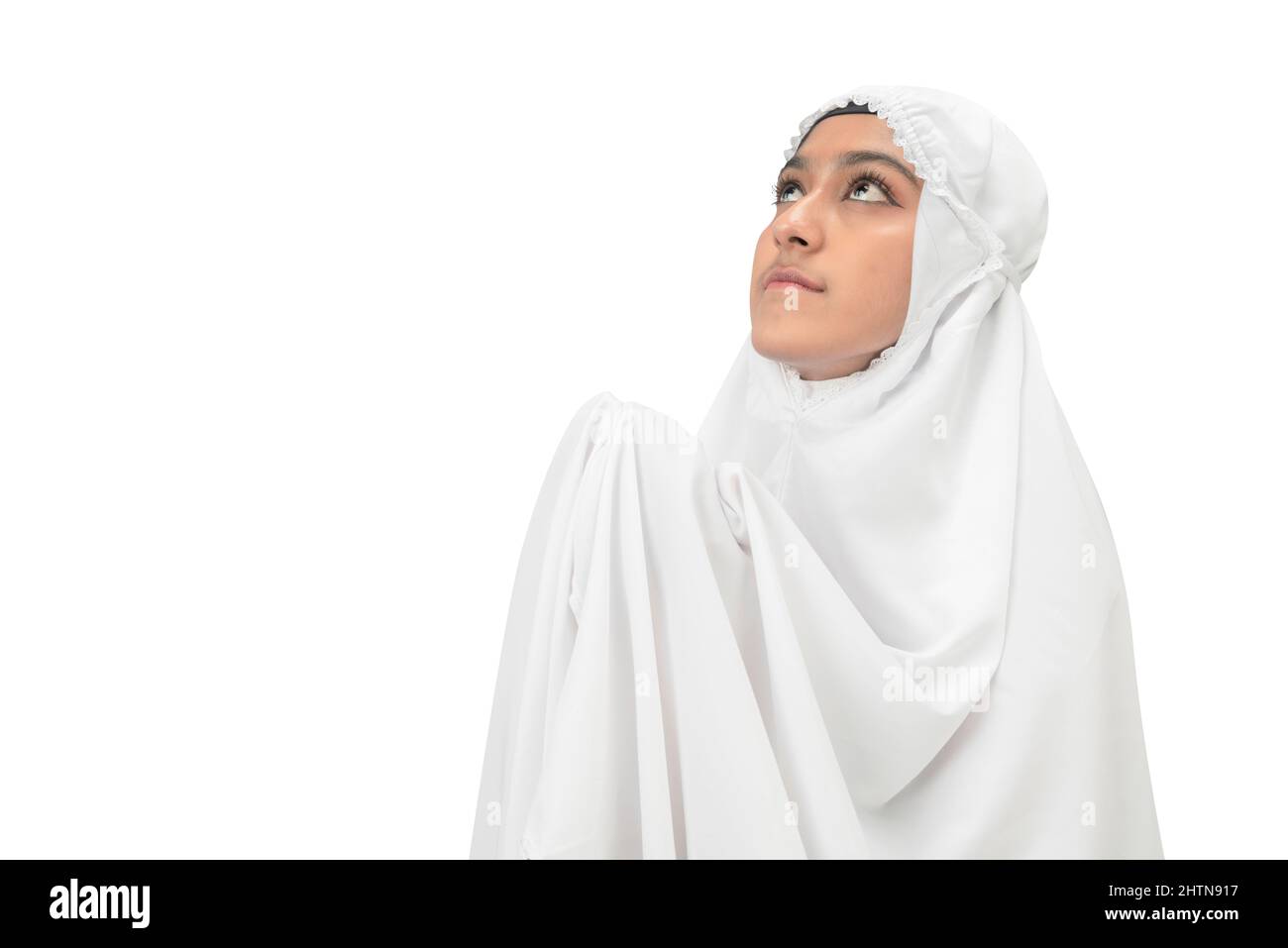 Asian Muslim woman in a veil standing while raised hands and praying ...