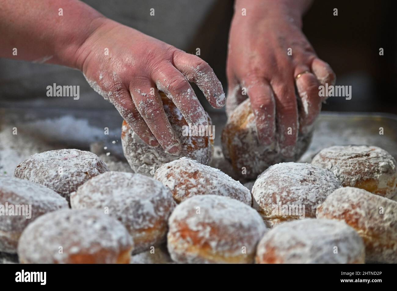 Nanticoke, United States. 01st Mar, 2022. A baker powders fastnacht to be sold for Fat Tuesday. Fat Tuesday is celebrated by eating Fastnacht and Paczki, Sanitary Bakery in Nanticoke, Pennsylvania experiences large lines of customers to buy their treats. At noon the bakery was almost sold out of the donuts. Credit: SOPA Images Limited/Alamy Live News Stock Photo