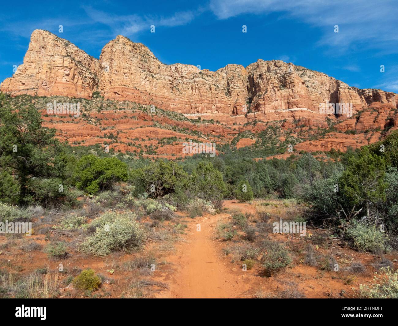 Dirt hiking trail leading to huge rock formations and mountains in the desert. Stock Photo