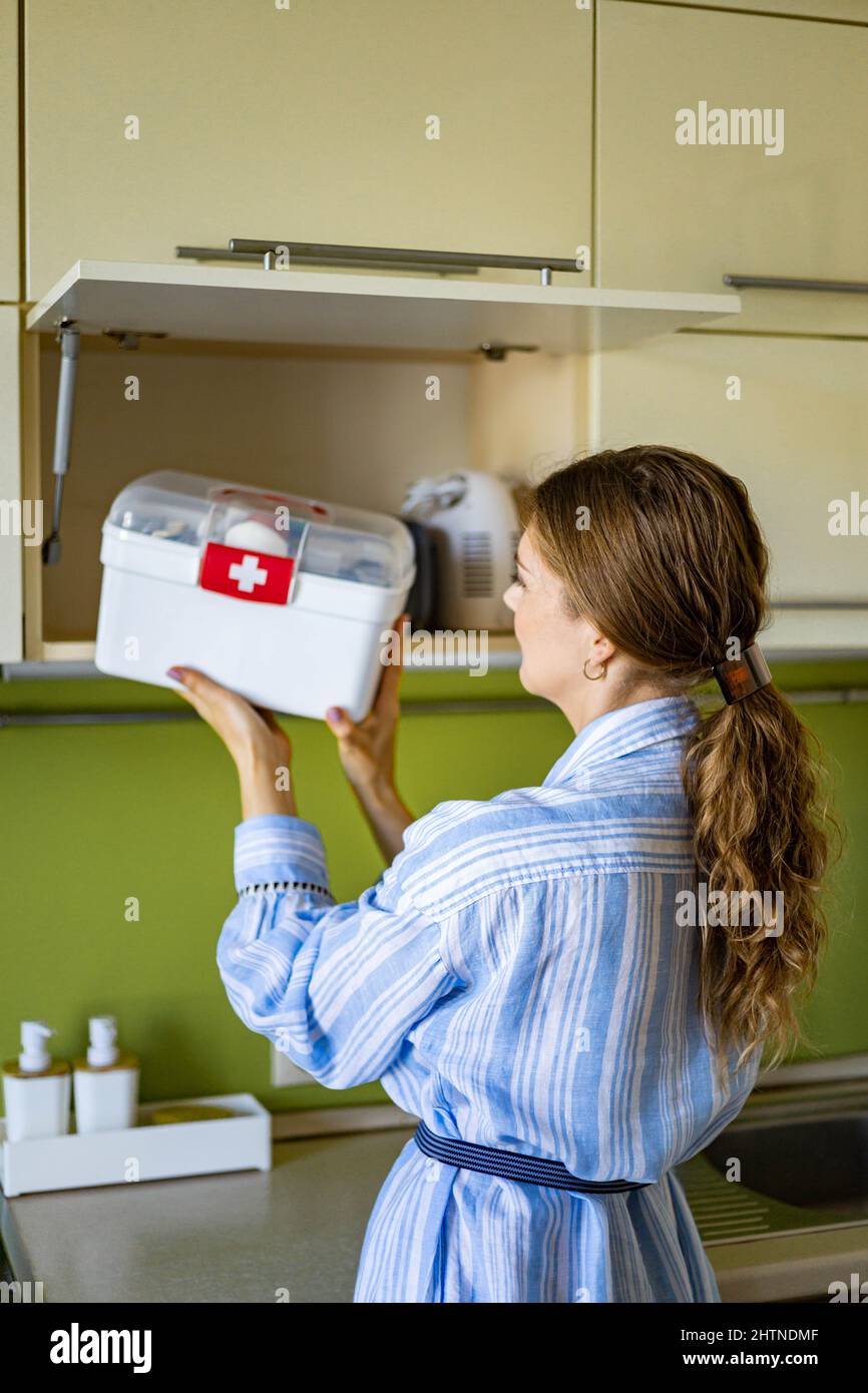 Domestic woman putting first aid kit with vitamins, drugs, antibiotics