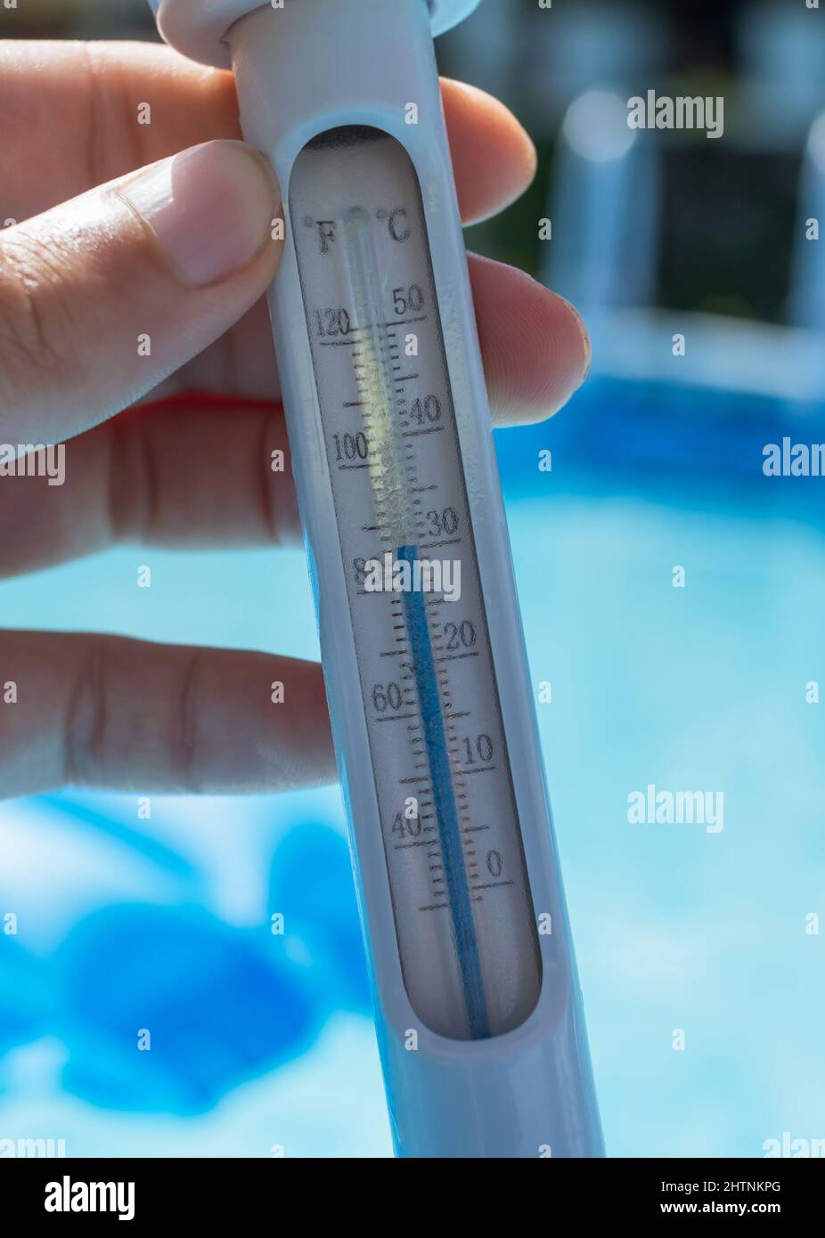 Close-up of a man holding a thermometer to measure the temperature of the  pool water. The thermometer reads 30 degrees Celsius or 85 Fahrenheit. The  b Stock Photo - Alamy