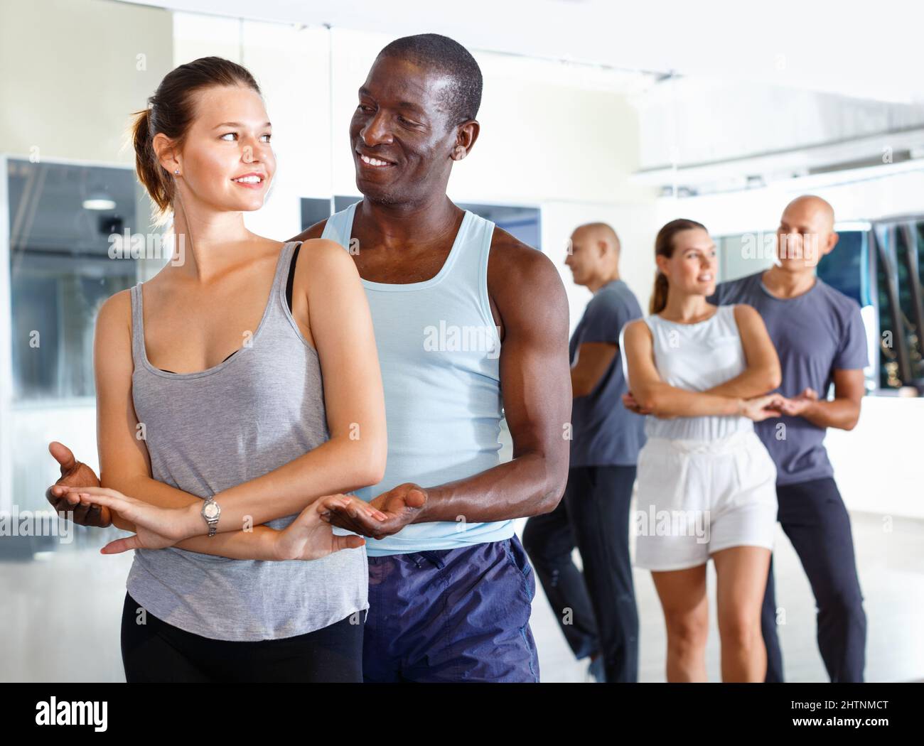 Young smiling people practicing passionate samba in dance class Stock Photo