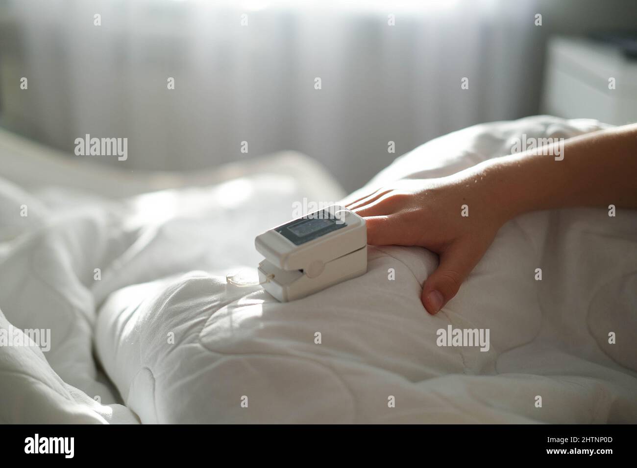 The teenager lies in bed and measure the oxygen saturation with a pulse oximeter. Asthma