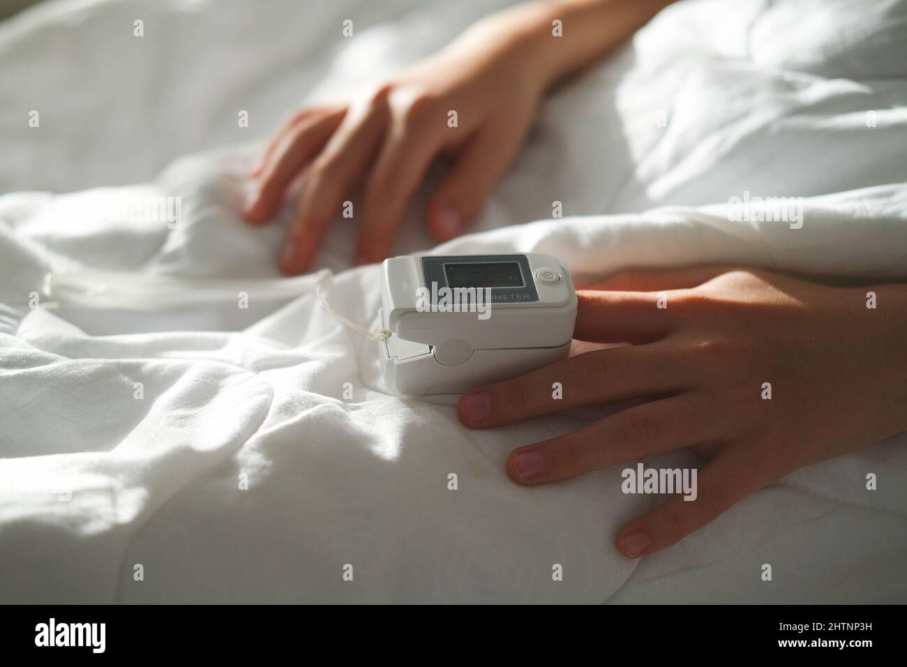 The teenager lies in bed and measure the oxygen saturation with a pulse oximeter. Asthma