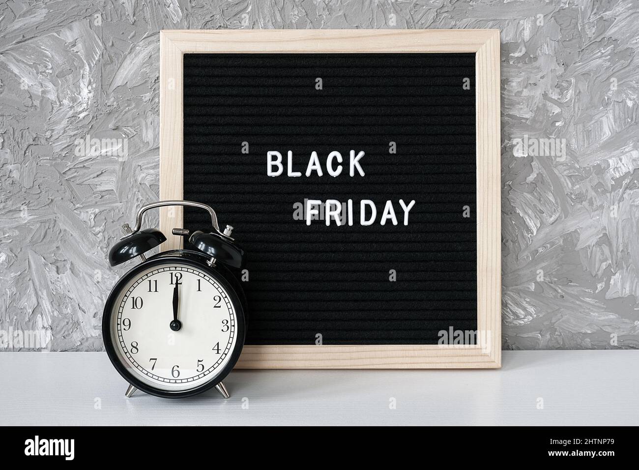 Text Black friday on black letter board and alarm clock on table against grey stone background. Concept Black friday , season sales time. Stock Photo