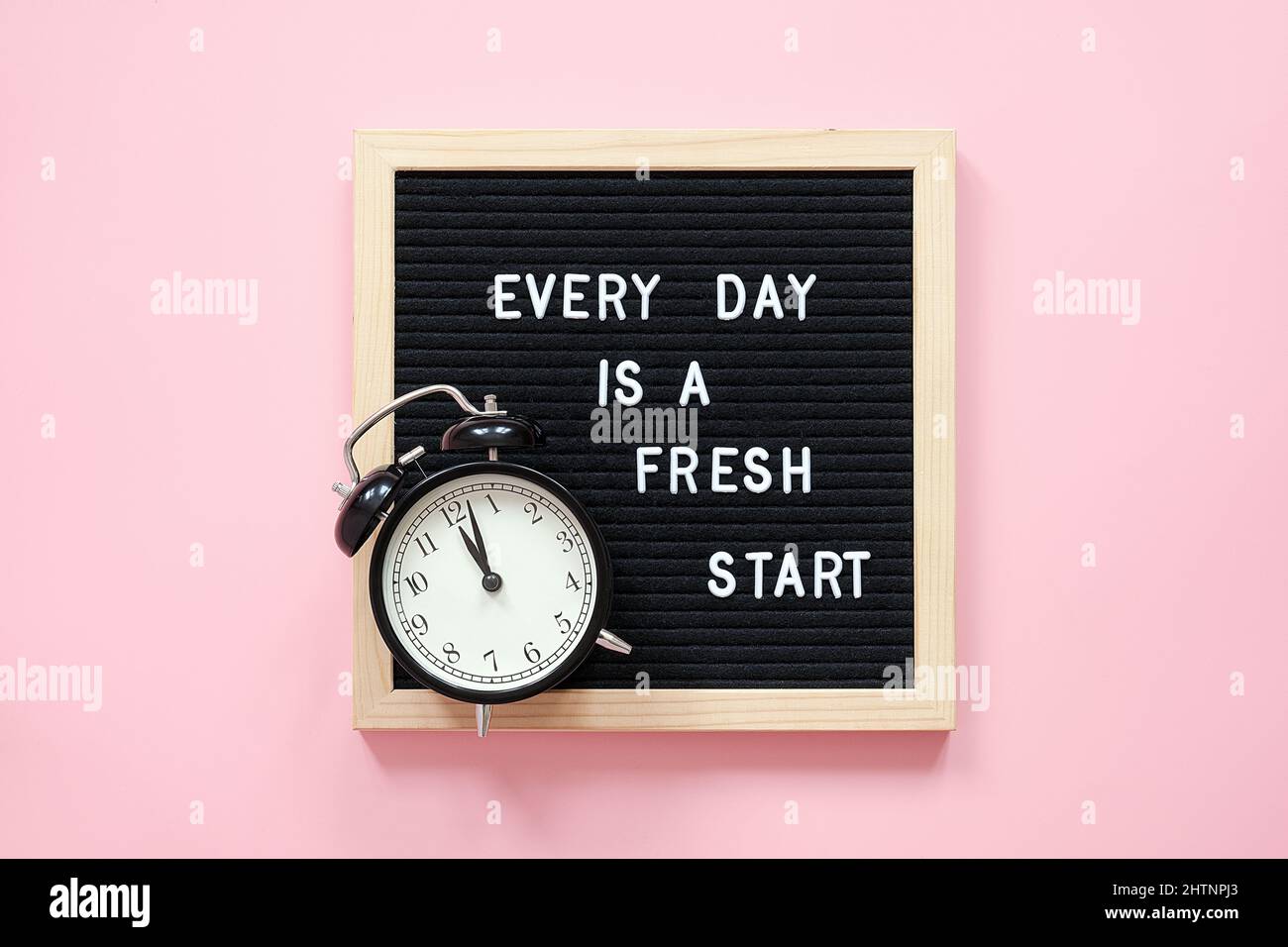 Every day is a fresh start. Motivational quote on black letter board and black alarm clock on pink background. Concept inspirational quote of the day. Stock Photo