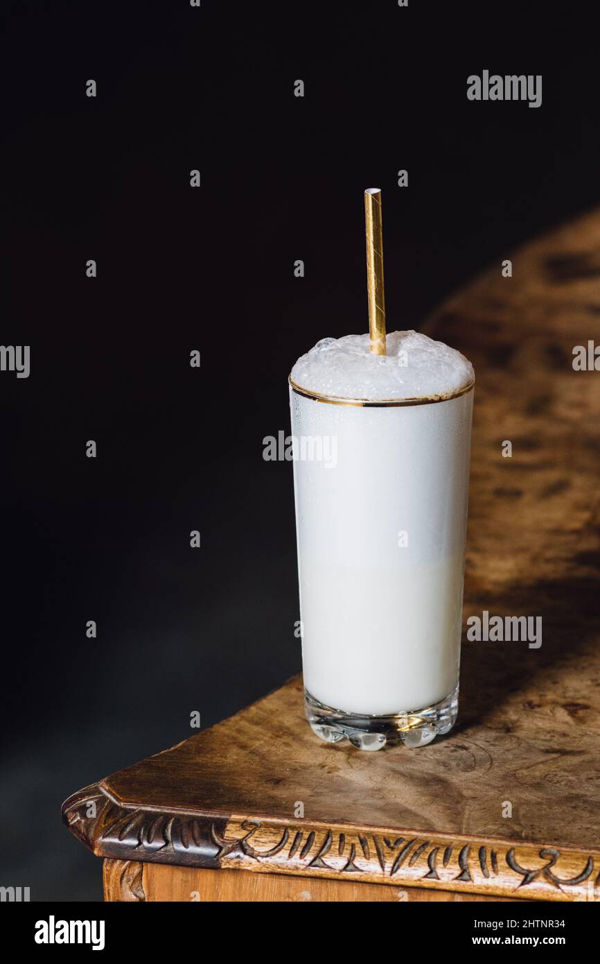 Ramos gin fizz milkshake white foam in goldrimmed tall glass with gold