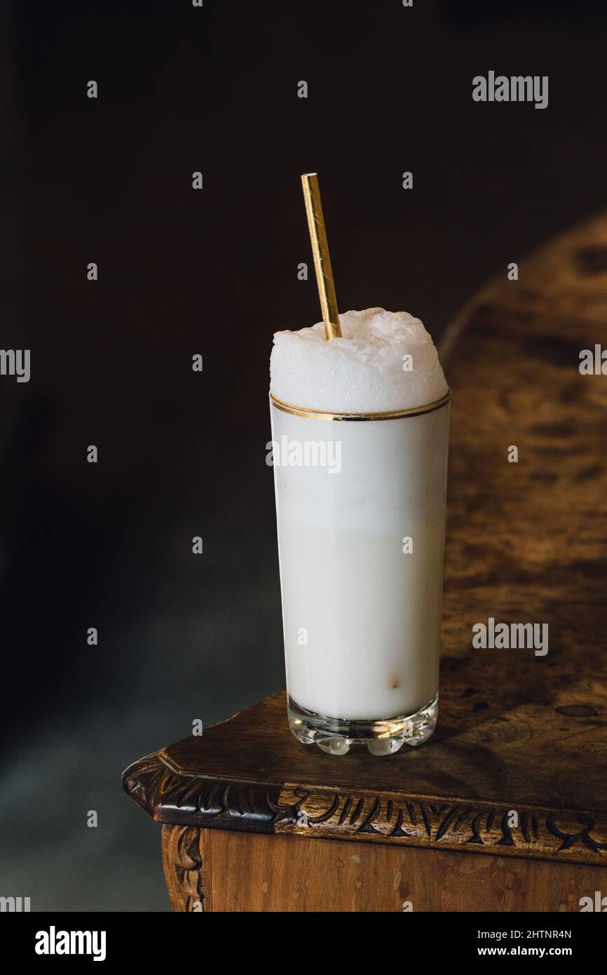 Ramos gin fizz milkshake white foam in goldrimmed tall glass with gold