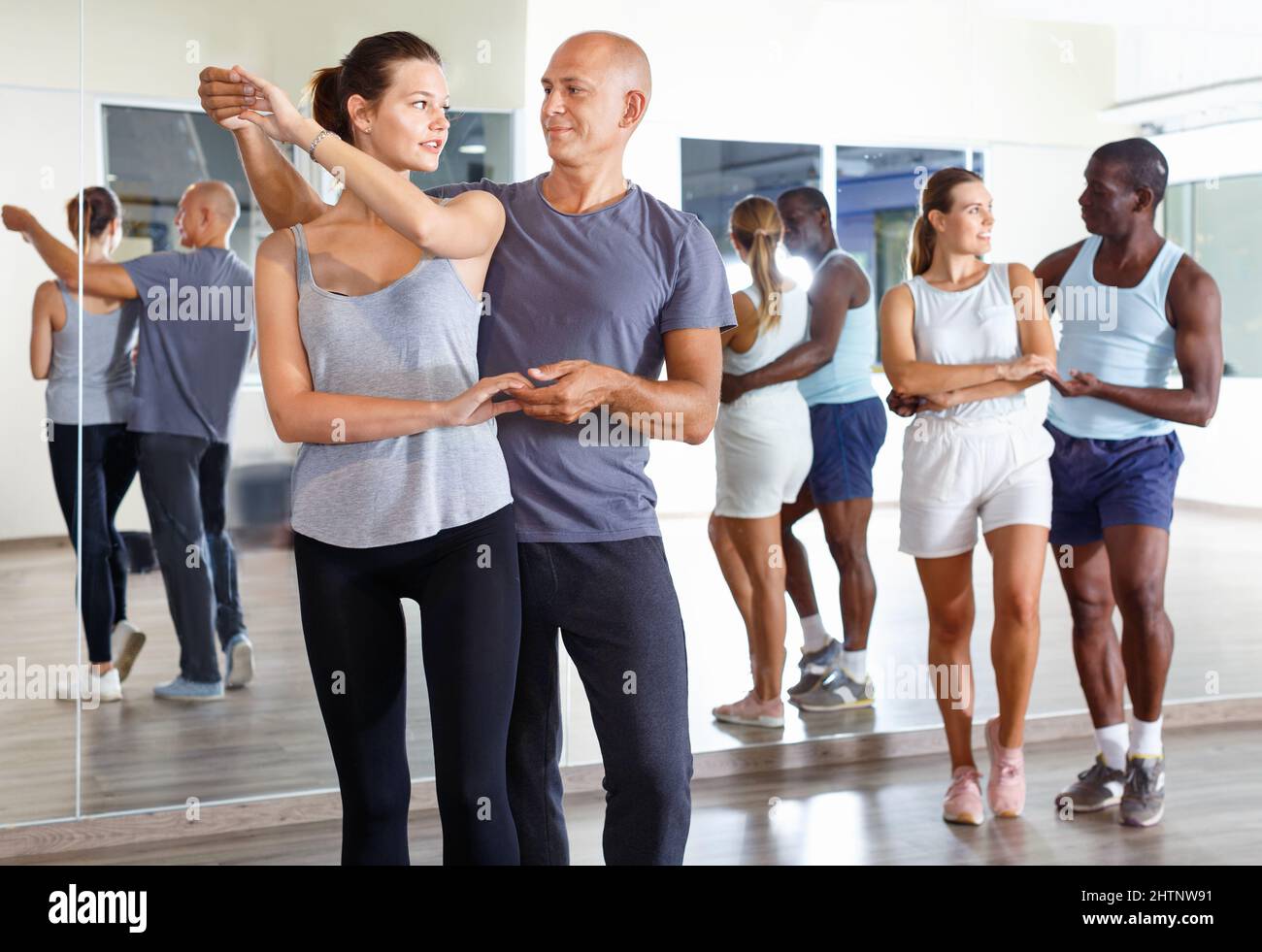 Young smiling people practicing passionate samba in dance class Stock Photo