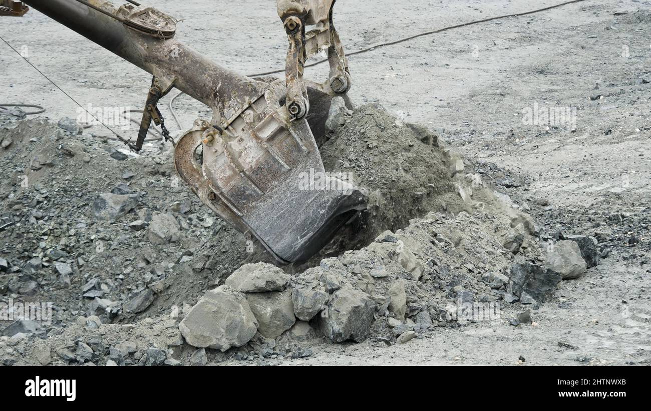 Scoop of excavator is digging hole. Excavator digs pit in ground for