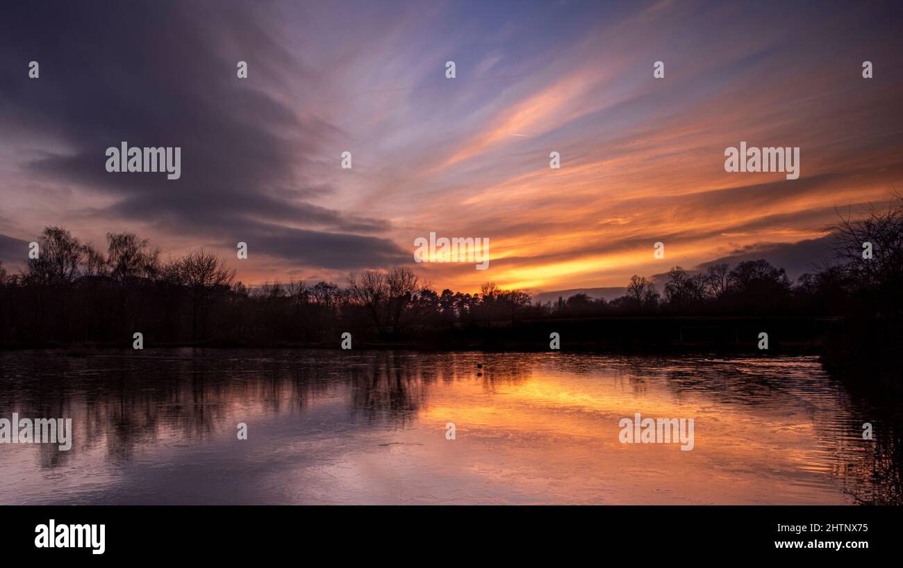 Colourful sky sunset over a frozen lake. Bulwell Hall Park Nottingham England UK Stock Photo