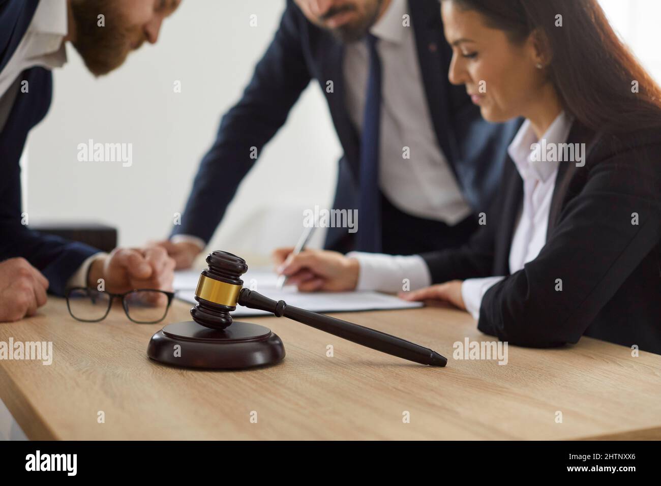 Close up of judge's gavel against background of lawyer and client