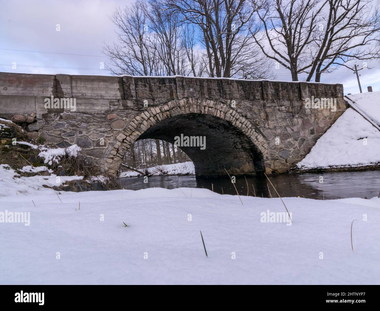 Winter Fast Bridge arched bridge over a fast flowing river, covered with snow Stock Photo ...