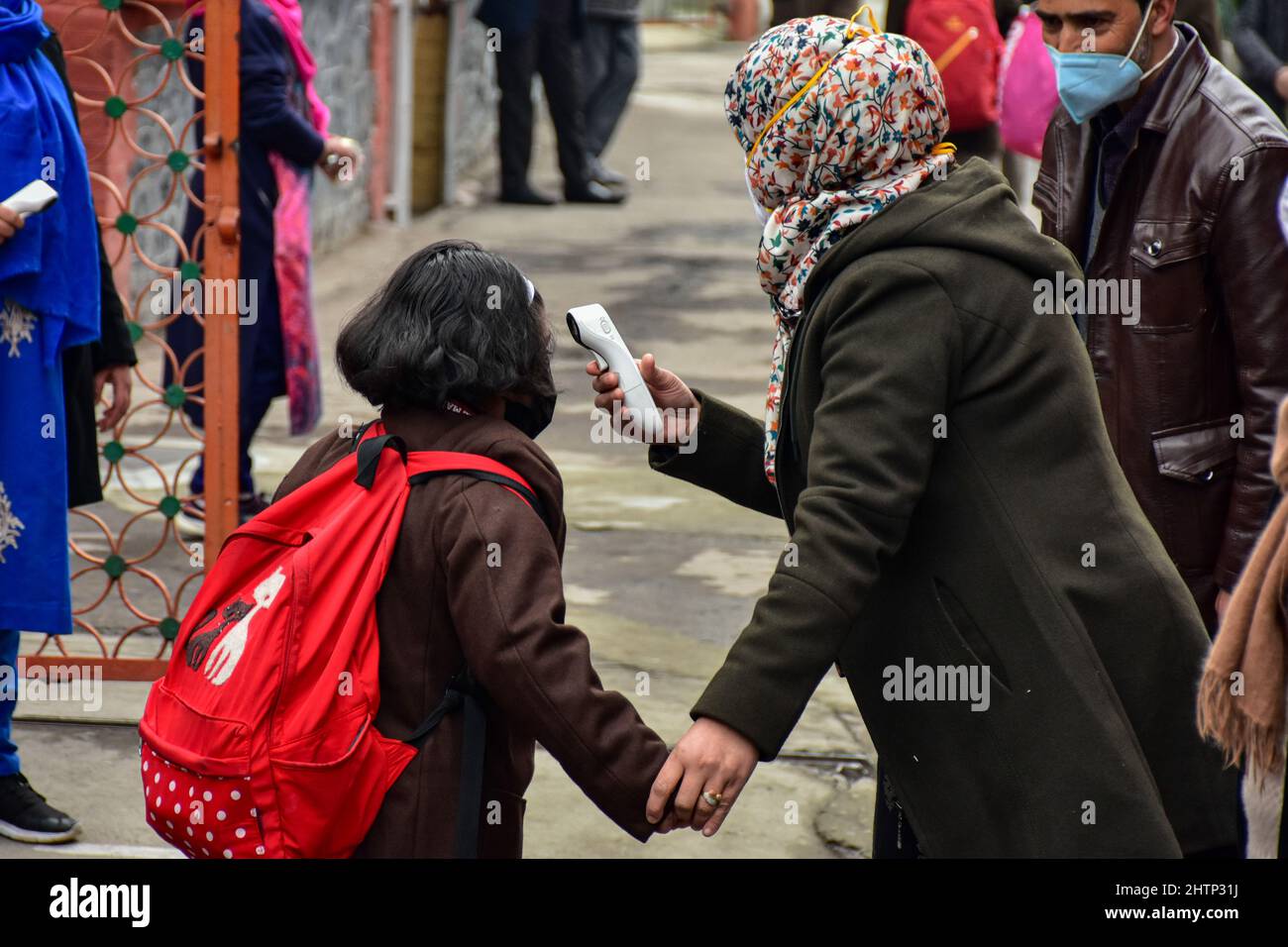 A school official checks the temperature of a student before entering into school building after one year of break due to the coronavirus pandemic in Srinagar. The schools in Kashmir valley reopened on Wednesday after almost one year. The schools were closed owing to the outbreak of COVID-19 in 2020. (Photo by Saqib Majeed / SOPA Images/Sipa USA) Stock Photo