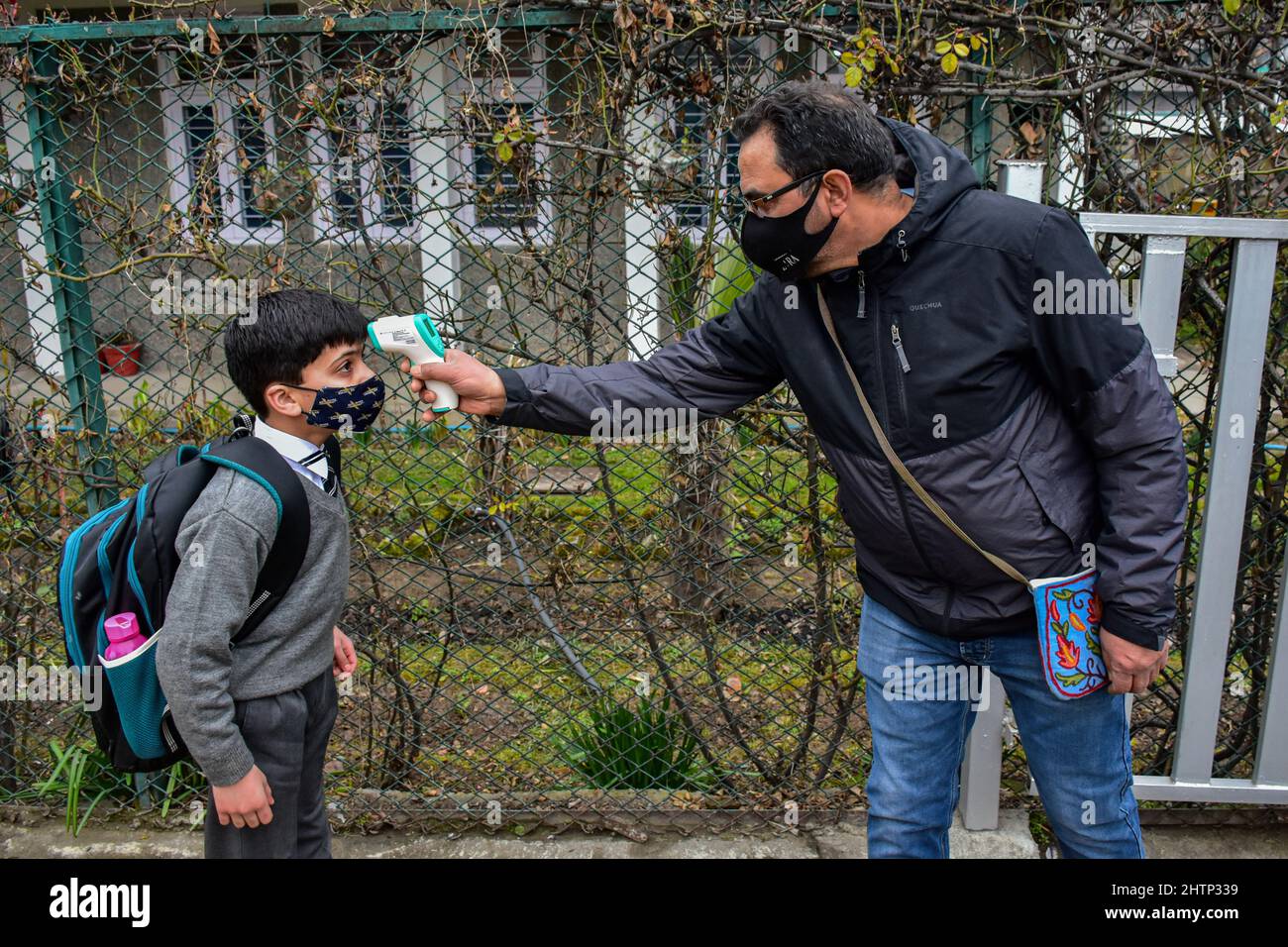 A school official checks the temperature of a student before entering into school building after one year of break due to the coronavirus pandemic in Srinagar. The schools in Kashmir valley reopened on Wednesday after almost one year. The schools were closed owing to the outbreak of COVID-19 in 2020. (Photo by Saqib Majeed / SOPA Images/Sipa USA) Stock Photo