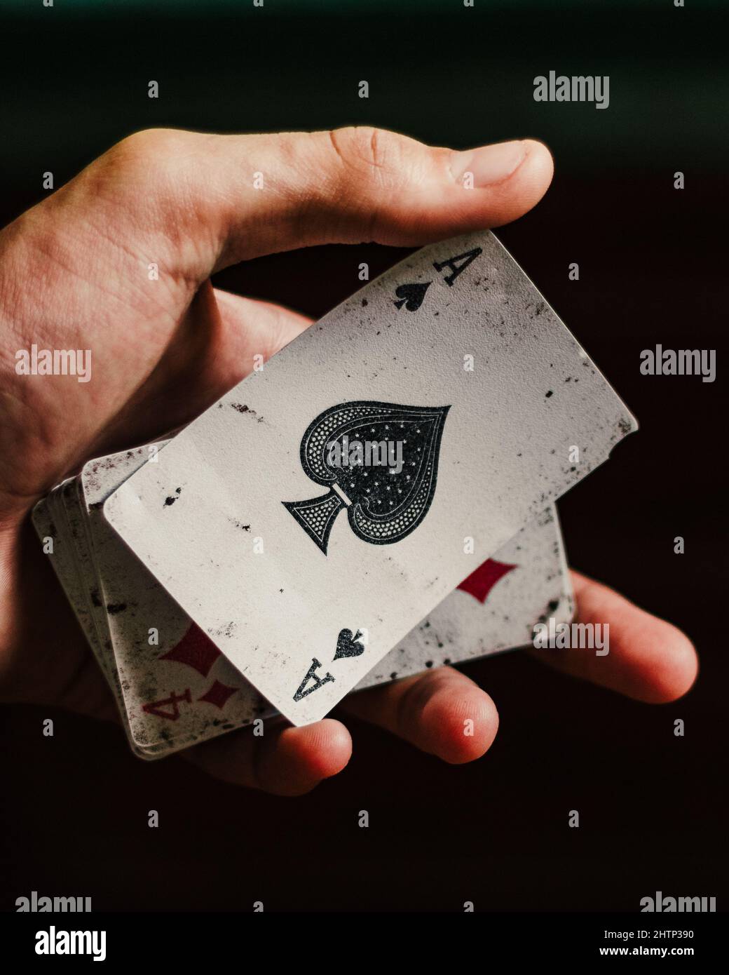 Man's hand holding old Ragged cardsAce of spades on a black background