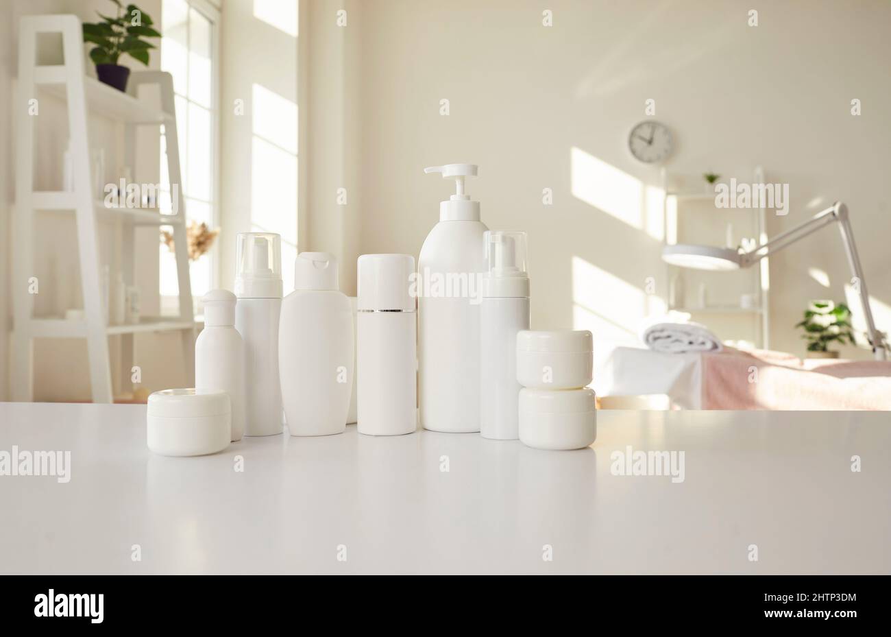 Set of different white clean bottles with natural cosmetics standing on table of beauty salon. Stock Photo