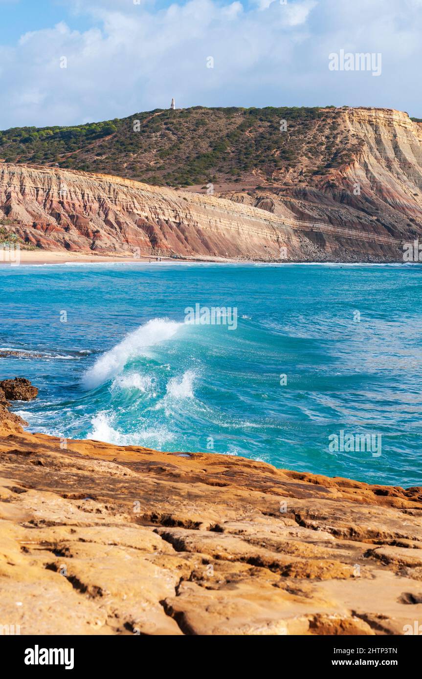 Coastline and beach area at Praia de Luz, rock formations and crashing turquoise waves Stock Photo