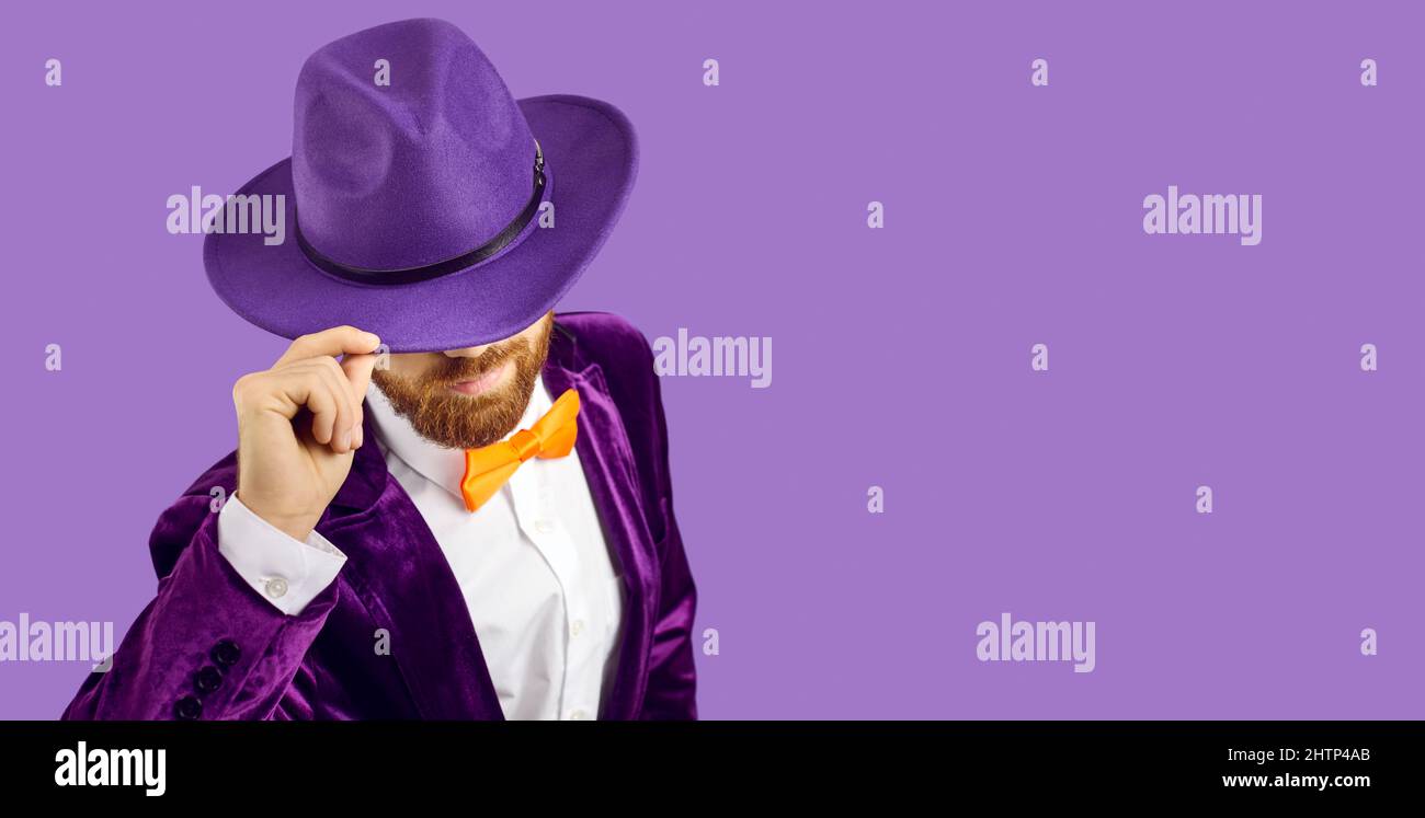 Handsome man in hat bows his head standing on purple copy space banner background Stock Photo