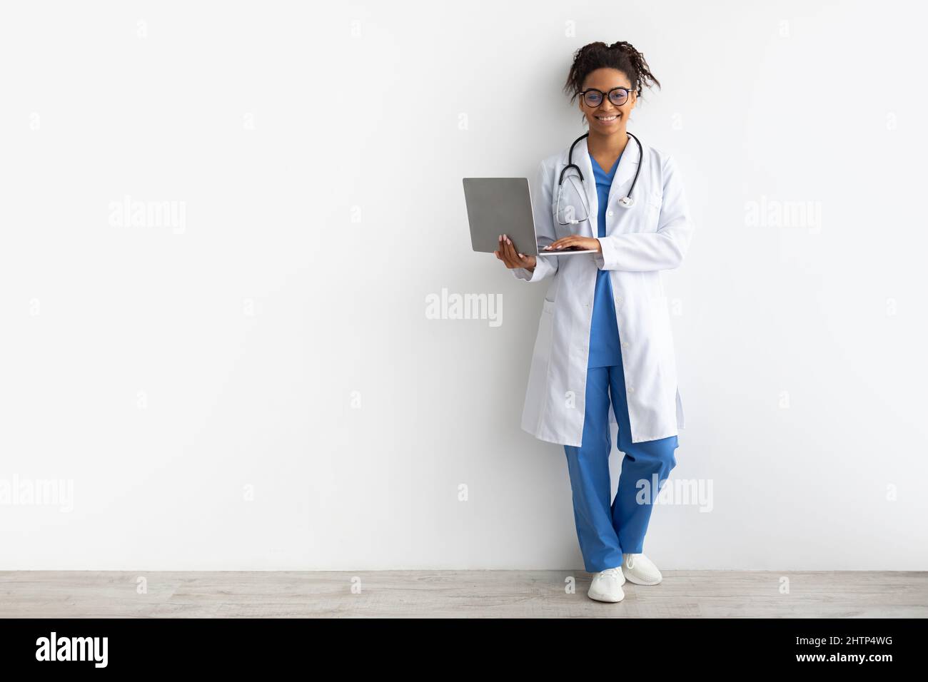 Smiling black female medical practitioner holding using laptop Stock Photo
