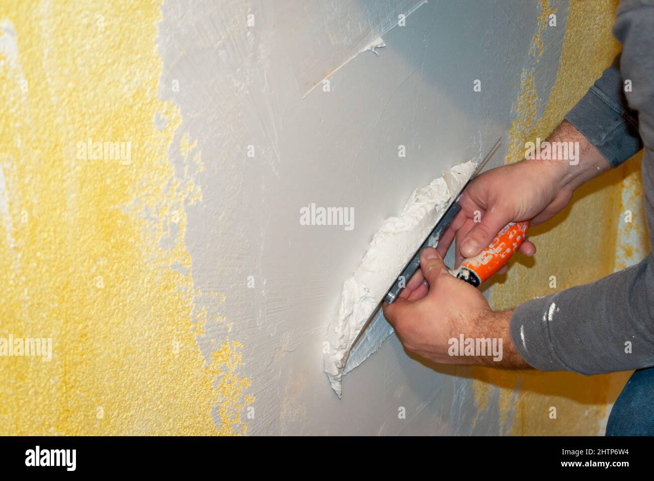 Plastering a wall with plaster in a house with a plaster knife and putty knife and heavy manual work Stock Photo