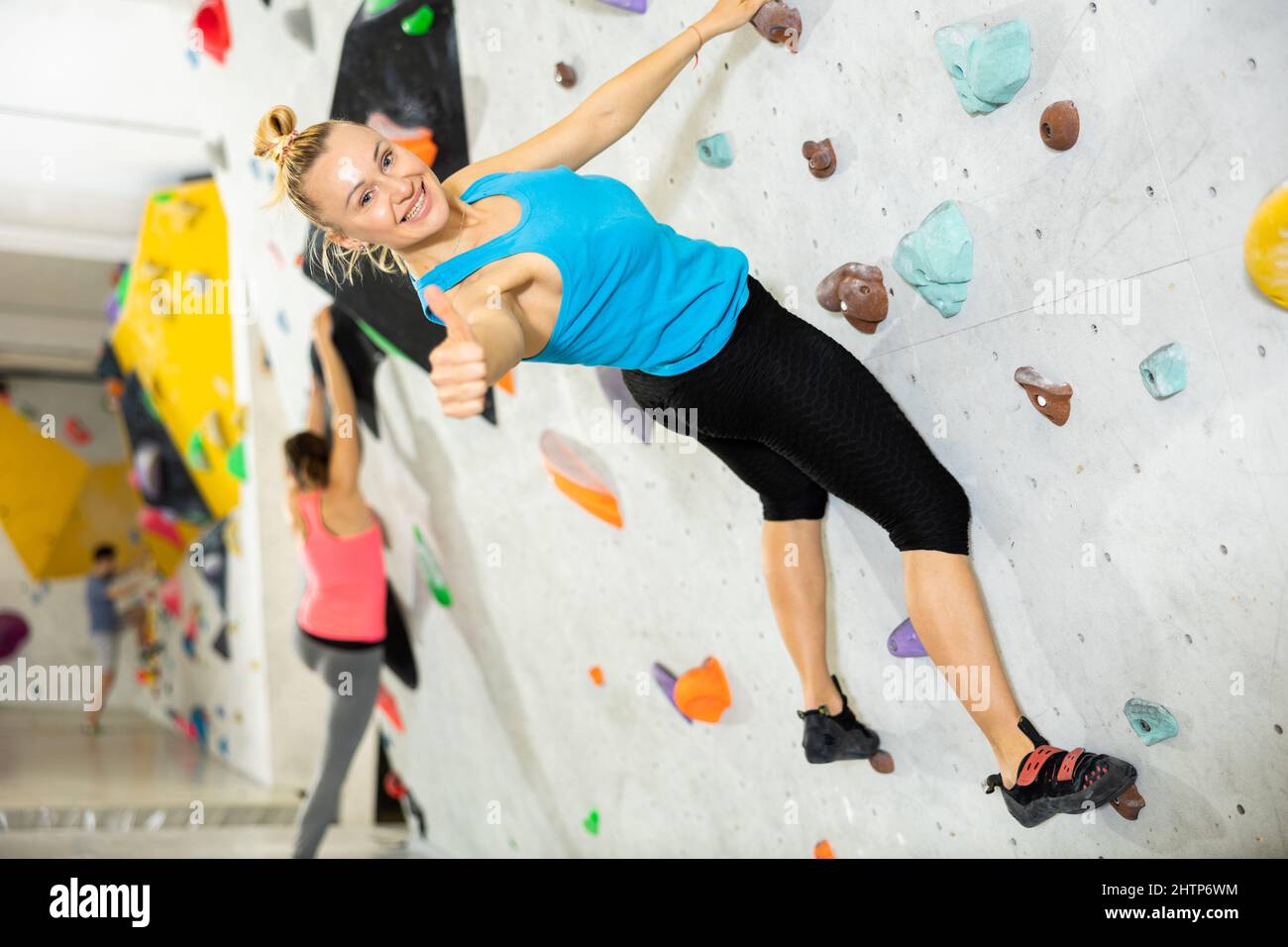 Young man making thumb up gesture while climbing in bouldering gym Stock Photo