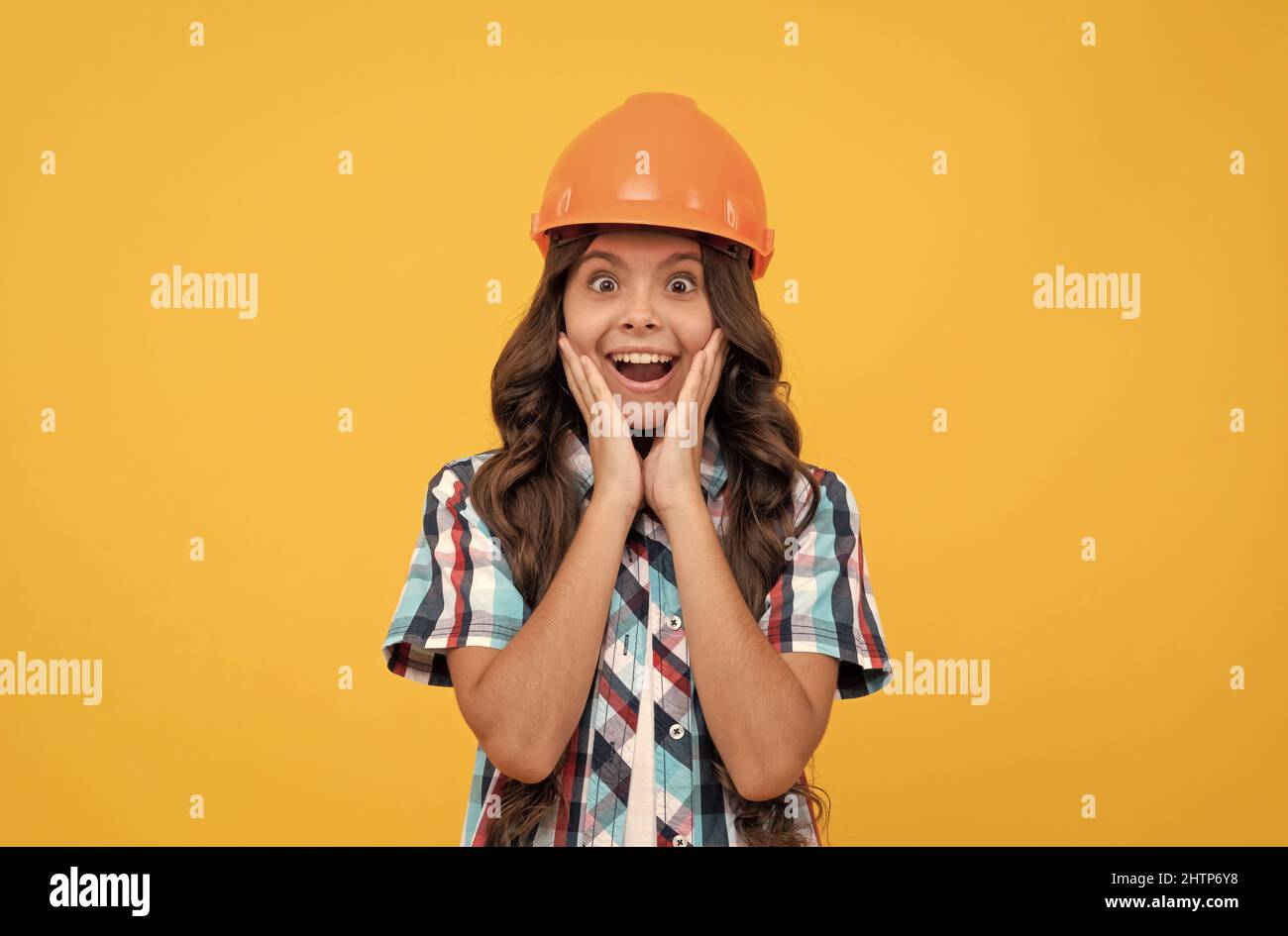 surprised teen girl with curly hair in construction helmet, carpenter Stock Photo