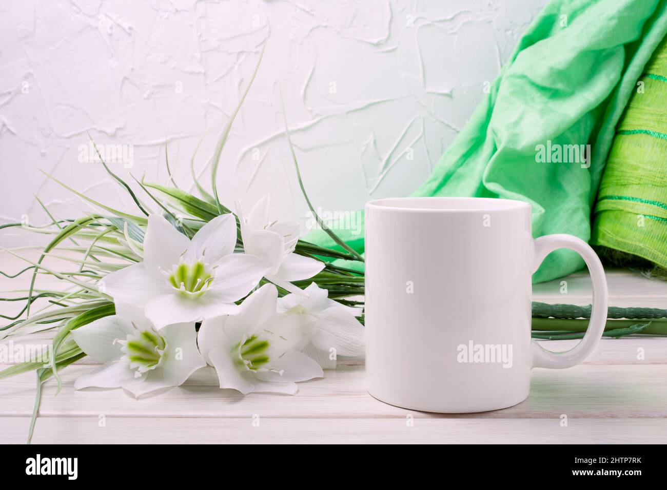 White coffee mug mockup with tender lily bouquet and green scarf. Empty mug mock up for design promotion, styled template Stock Photo