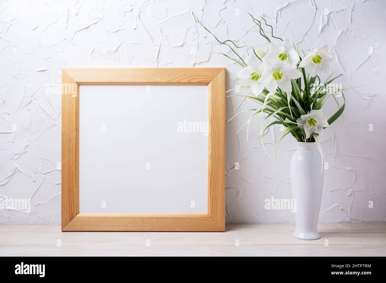 Wooden square picture frame mockup with tender lily bouquet in the white vase. Empty frame mock up for presentation design. Template framing for moder Stock Photo