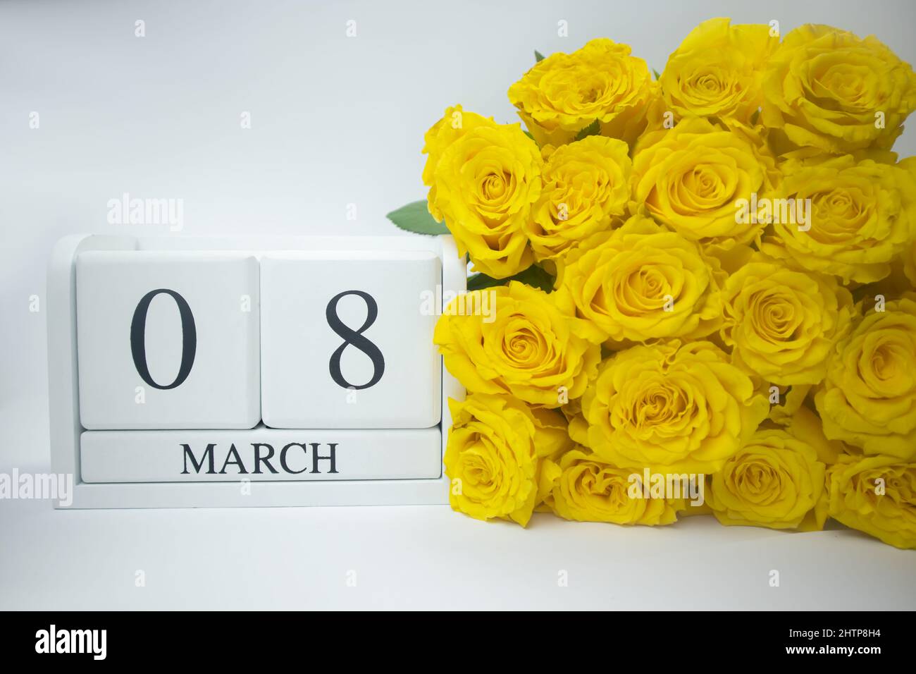 Wooden calendar March 8 and yellow roses on a white background.  Stock Photo
