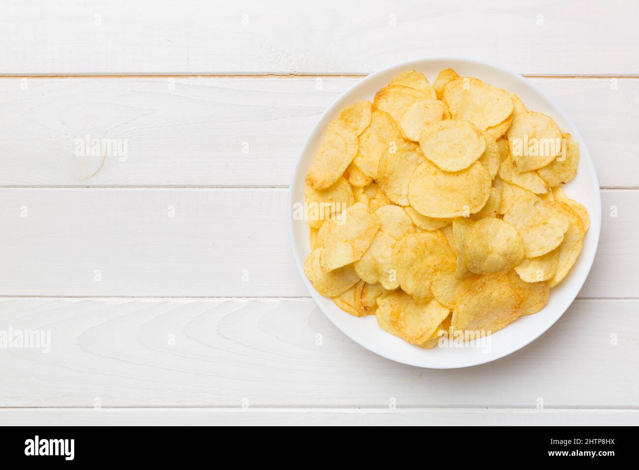 Potato chips on bowl isolated on colored background. Delicious crispy
