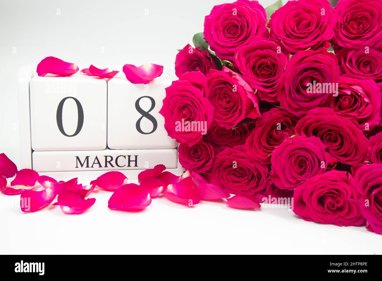 Wooden calendar March 8 and pink roses on a white background and rose petals Stock Photo