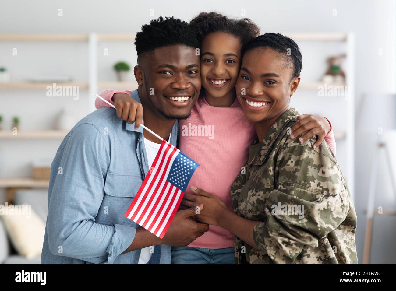 Happy girl with flag of US hugging her parents Stock Photo