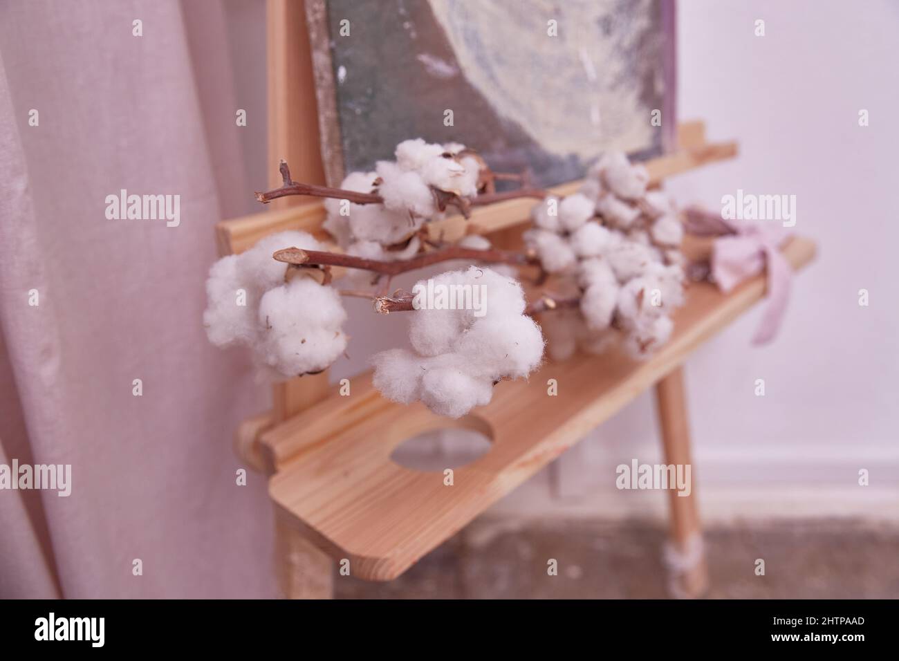 branch of a cotton plant lies on a wooden easel. Interior design of the creative artist's home space. Stock Photo