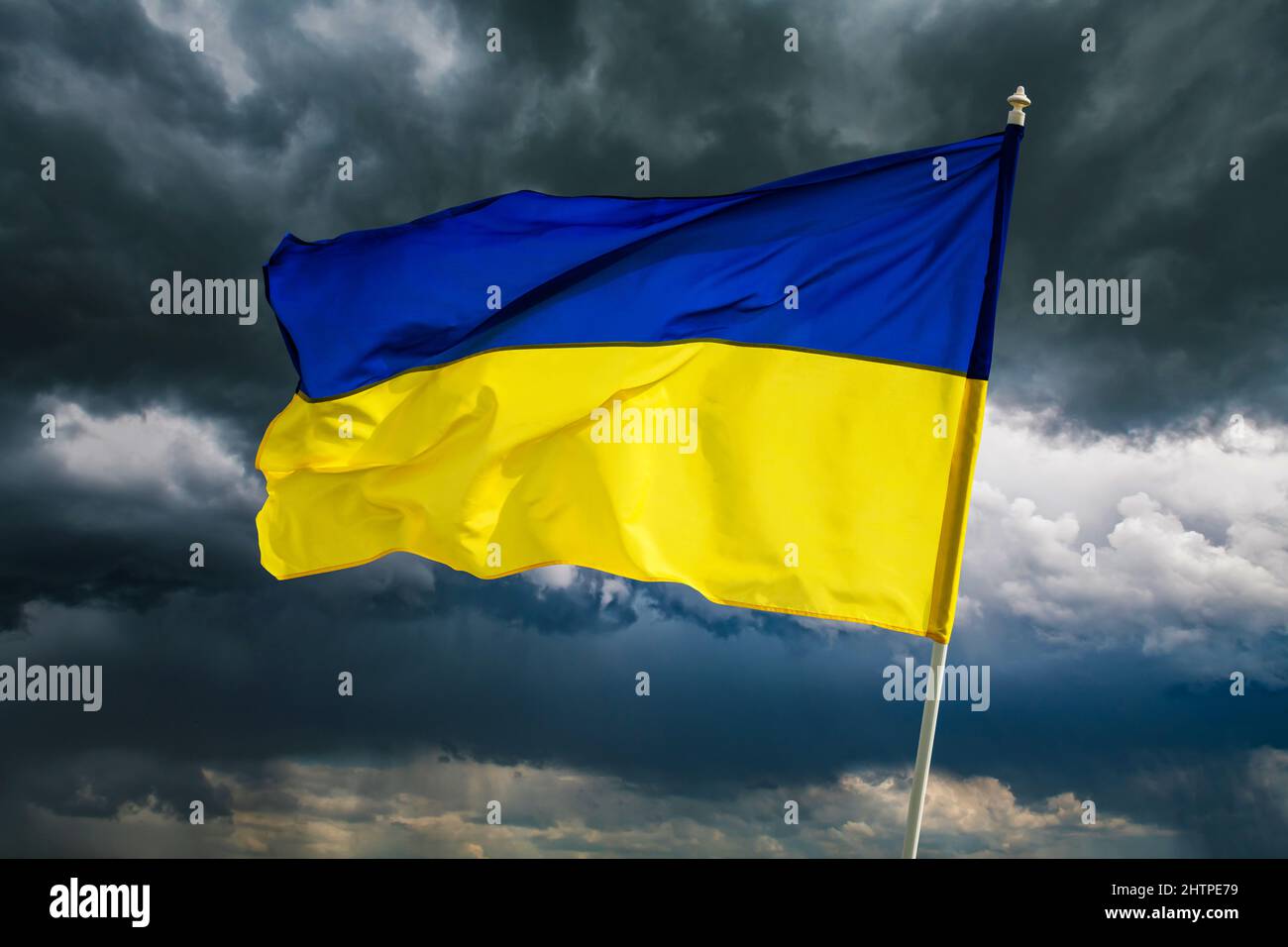 Ukrainian blue and yellow bicolor national flag on dark cloudy dramatic sky background. Ukraine fight for Freedom concept Stock Photo