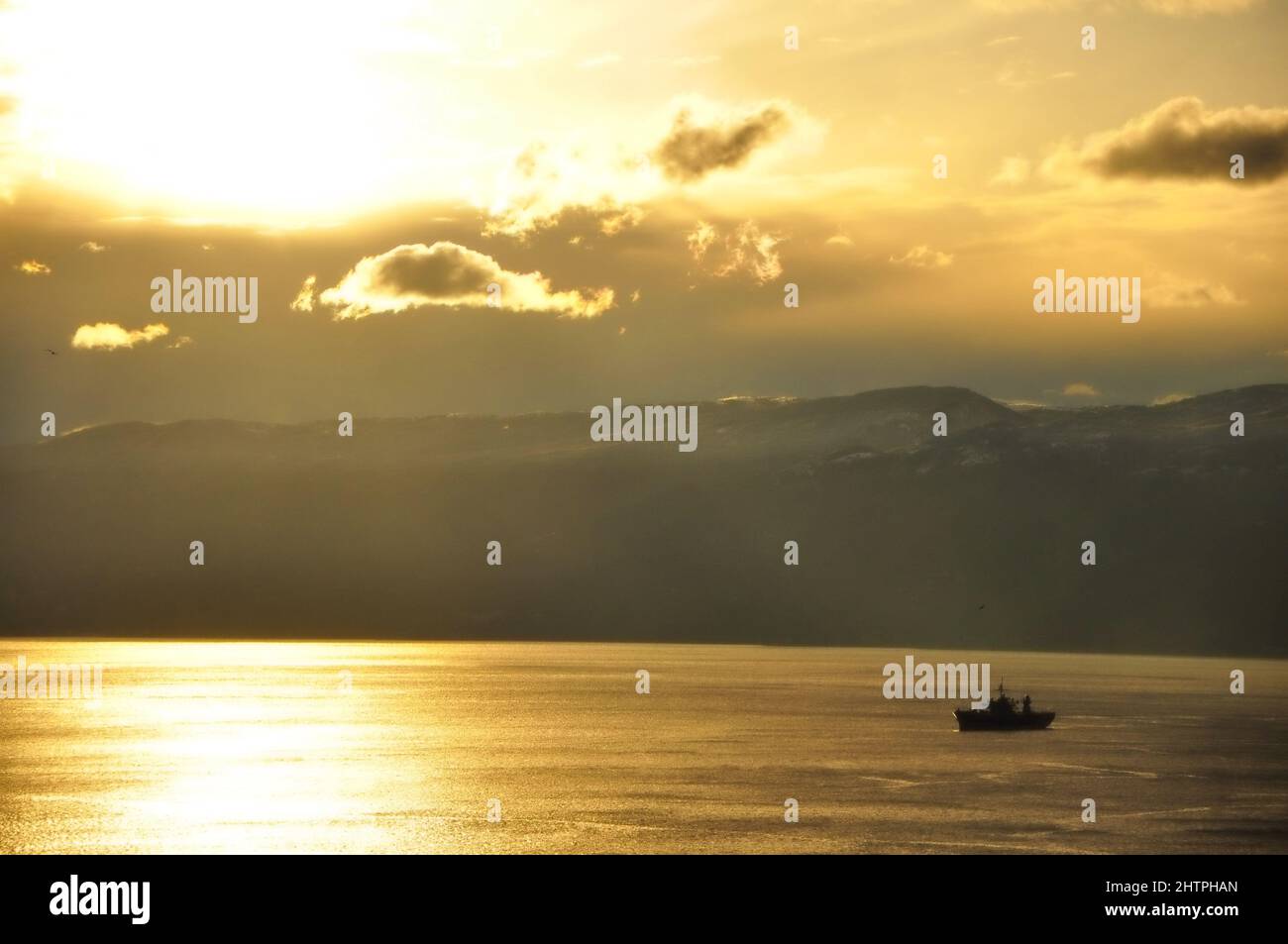 Liquid Gold Holiday boat. Fishing boat surrounded by sun glitters sea on beautiful sunset. Fishboat and panoramic view from Rijeka to Croatian island. Stock Photo