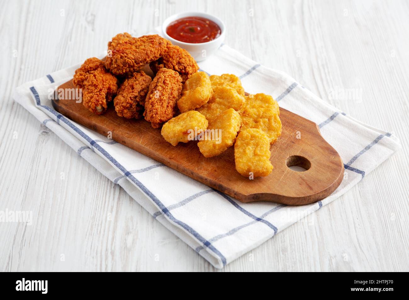 Homemade Crispy Fried Chicken Wings and Nuggets with Sweet and Sour Sauce on a rustic wooden