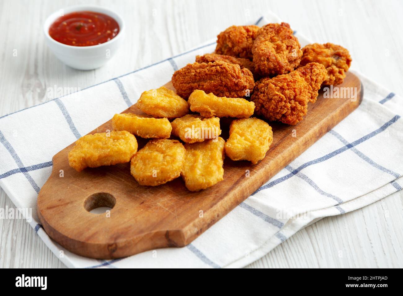 Homemade Crispy Fried Chicken Wings and Nuggets with Sweet and Sour Sauce on a rustic wooden