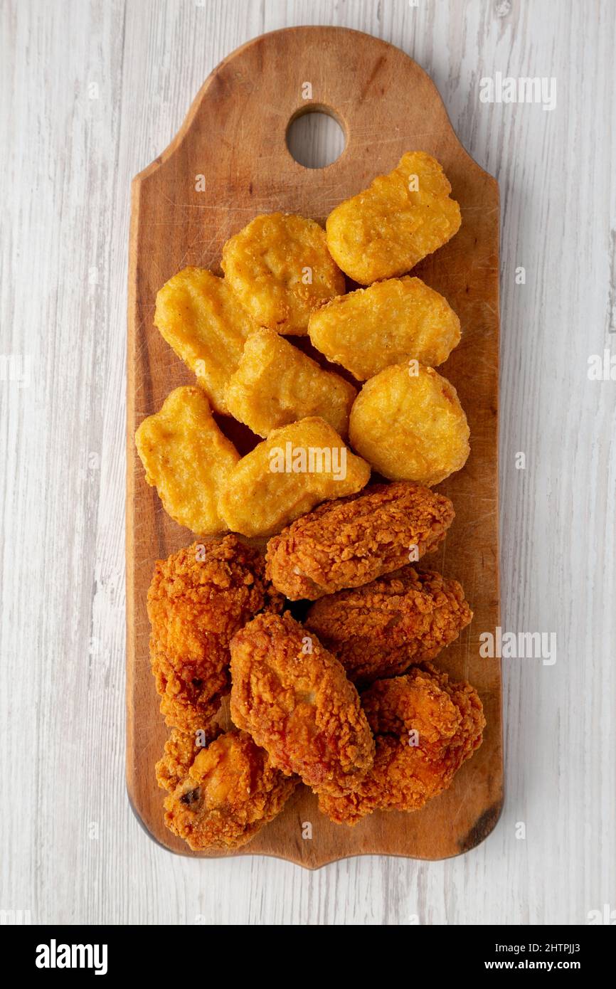 Homemade Crispy Fried Chicken Wings and Nuggets on a rustic wooden board, top view. Flat lay