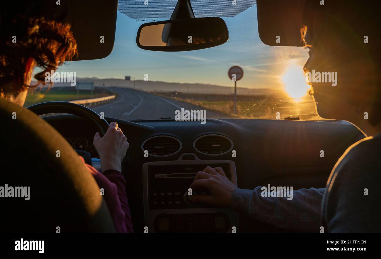 Couple driving at sunset turning up the radio Stock Photo