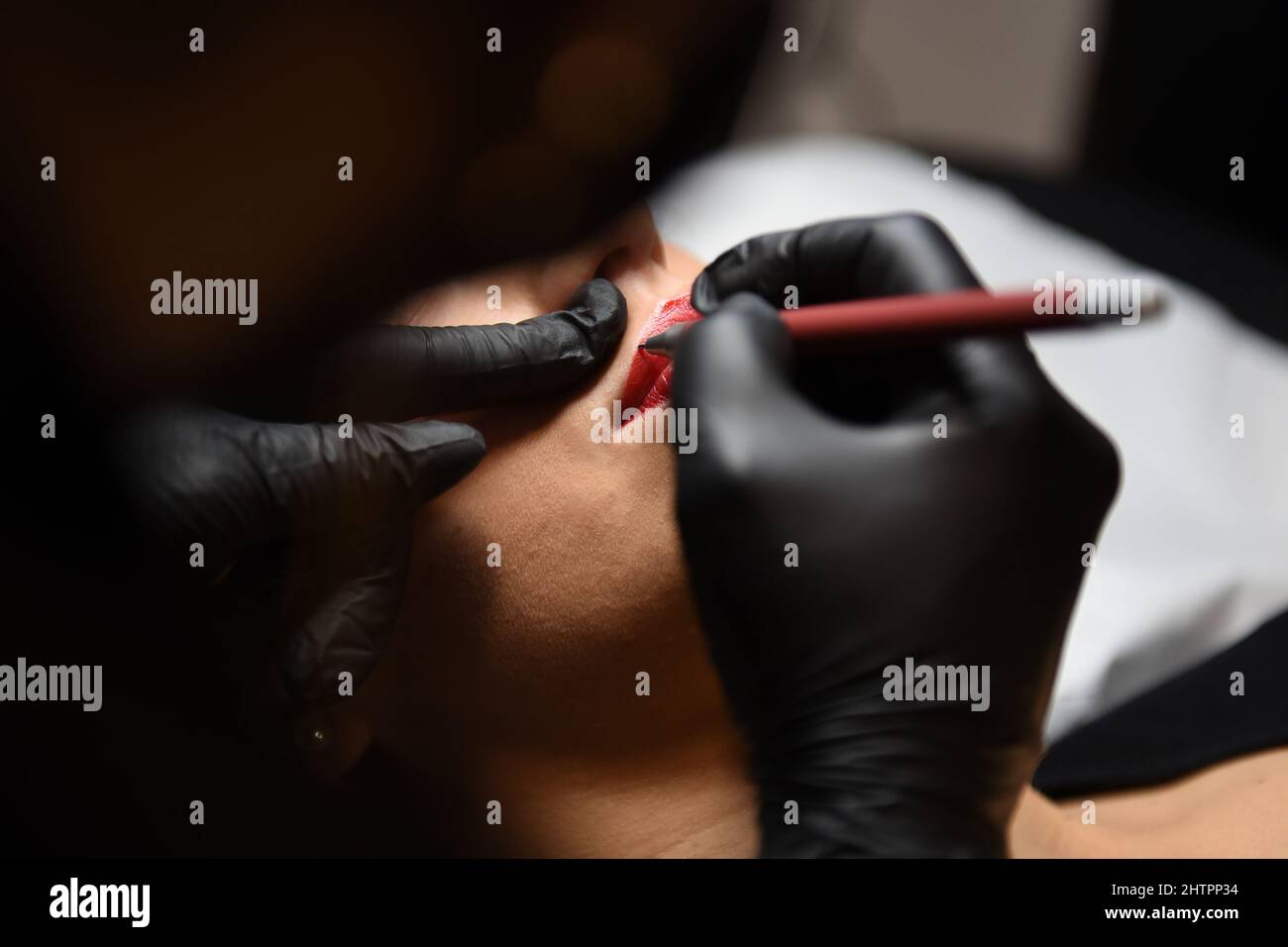 Cosmetologist applying permanent makeup on woman lips, microblading process Stock Photo