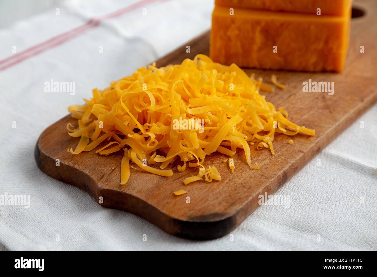 Rustic Cheddar Lumpy Shredded Sharp Cheddar Cheese on a rustic wooden board, side view Stock ...