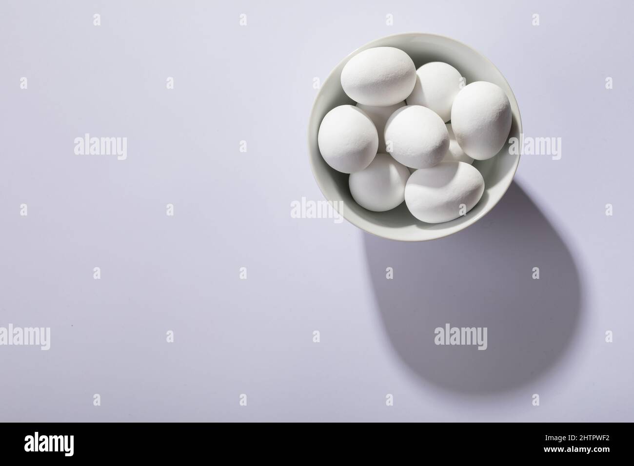 Overhead view of white eggs in bowl on table with empty space Stock Photo