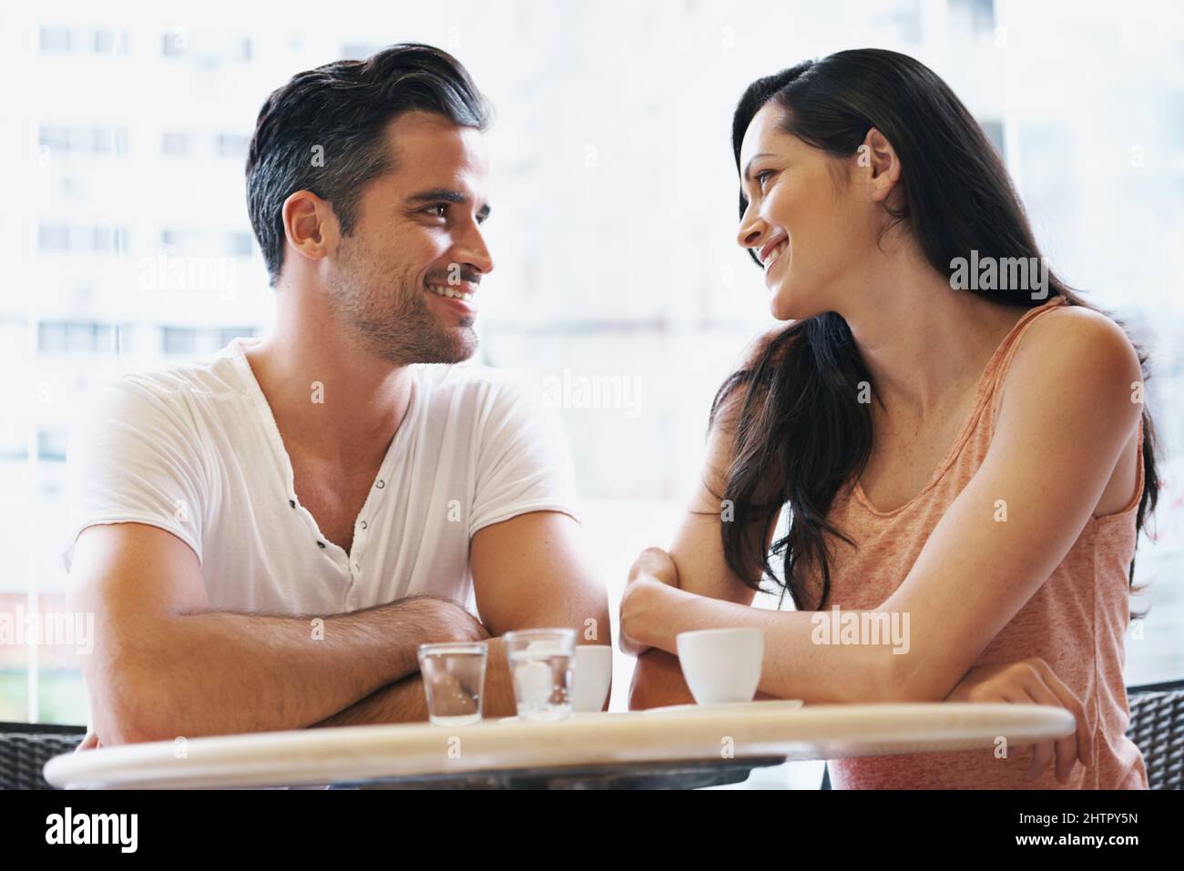 Blissfully happy in the bistro. Shot of a young couple grabbing a cup of coffee together Stock