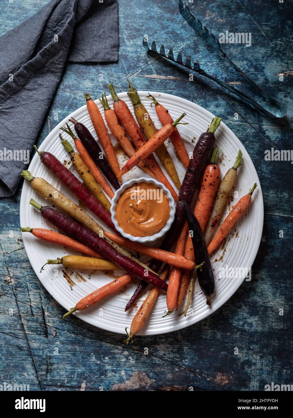 Roasted rainbow carrots on a round plate with sriracha mayo dip in the middle. Stock Photo