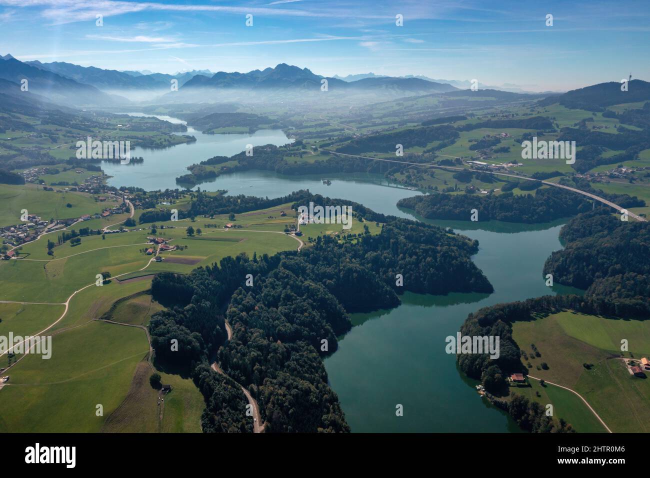 Aerial view of the Lac de la Gruyere, a lake in the canton of Fribourg, Switzerland. The lake winds through the hills of the region and is surrounded by a layer of trees. High quality photo Stock Photo