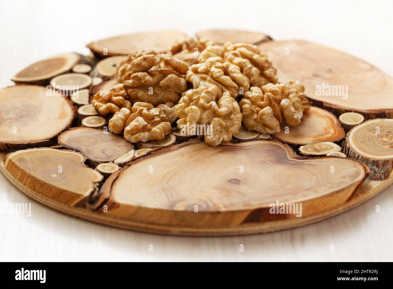 Peeled halves of walnuts on a tray made from slices of tree trunks. Close up Stock Photo