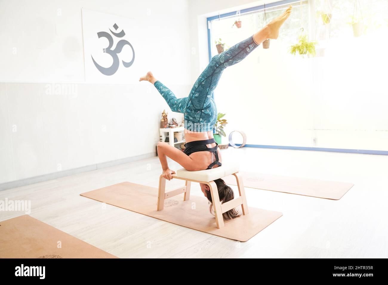 fit woman in headstand using a professional yoga bench. feet up