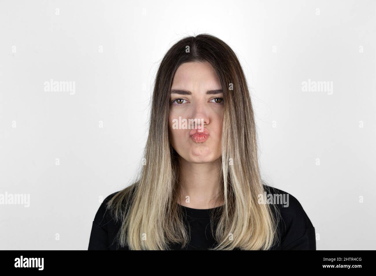 The girl in casual clothes,  pursed lips. White studio background. Stock Photo